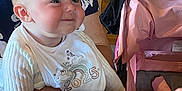 Katie is registered to the contest to win money with this photo: baby, child, infant, bib, smiling, person, indoor, restaurant, table, chair, stroller, adult, clothing, wooden_floor, fork, knife, menu, happy, face, holding