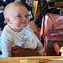baby, child, infant, bib, smiling, person, indoor, restaurant, table, chair, stroller, adult, clothing, wooden_floor, fork, knife, menu, happy, face, holding