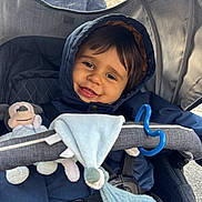 Mathéïs a rejoint le concours — aidez-le/la à gagner de superbes lots ! toddler, child, smiling, hooded_jacket, stroller, plush_toy, blue_cloth, baby, happy, outdoor, seatbelt, face, person, cute, infant, warm_clothing, toy, baby_stroller, closeup, portrait