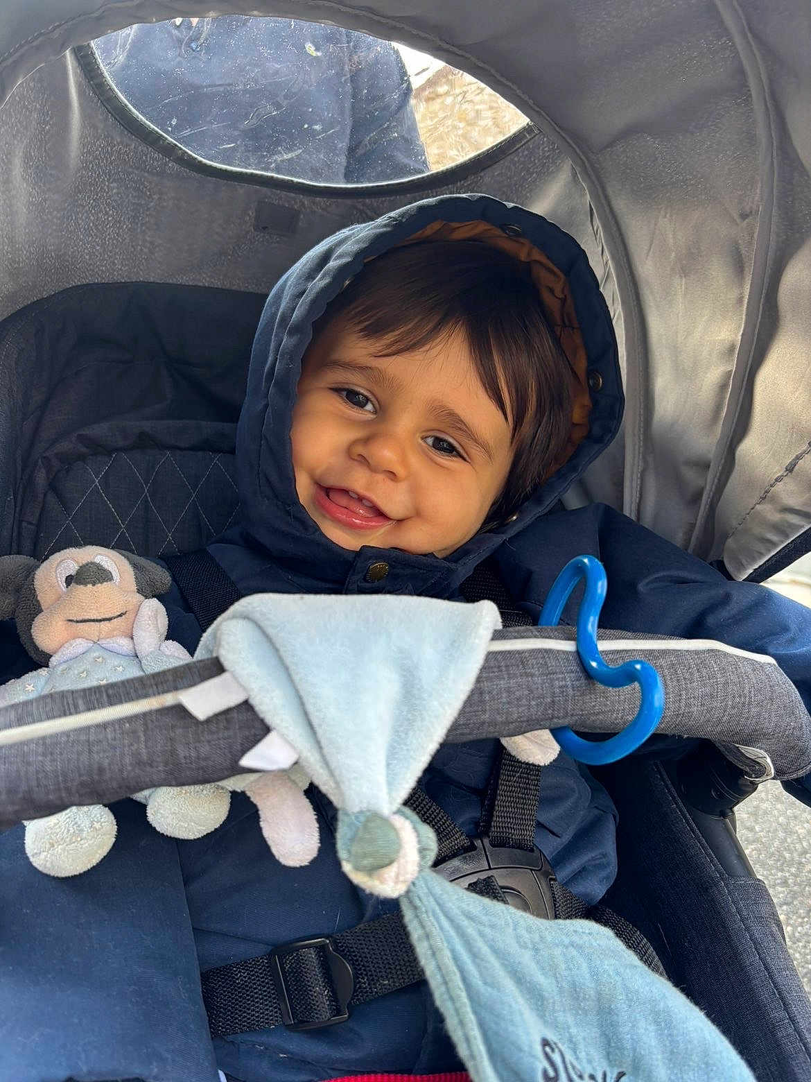 Mathéïs a rejoint le concours — aidez-le/la à gagner de superbes lots ! toddler, child, smiling, hooded_jacket, stroller, plush_toy, blue_cloth, baby, happy, outdoor, seatbelt, face, person, cute, infant, warm_clothing, toy, baby_stroller, closeup, portrait