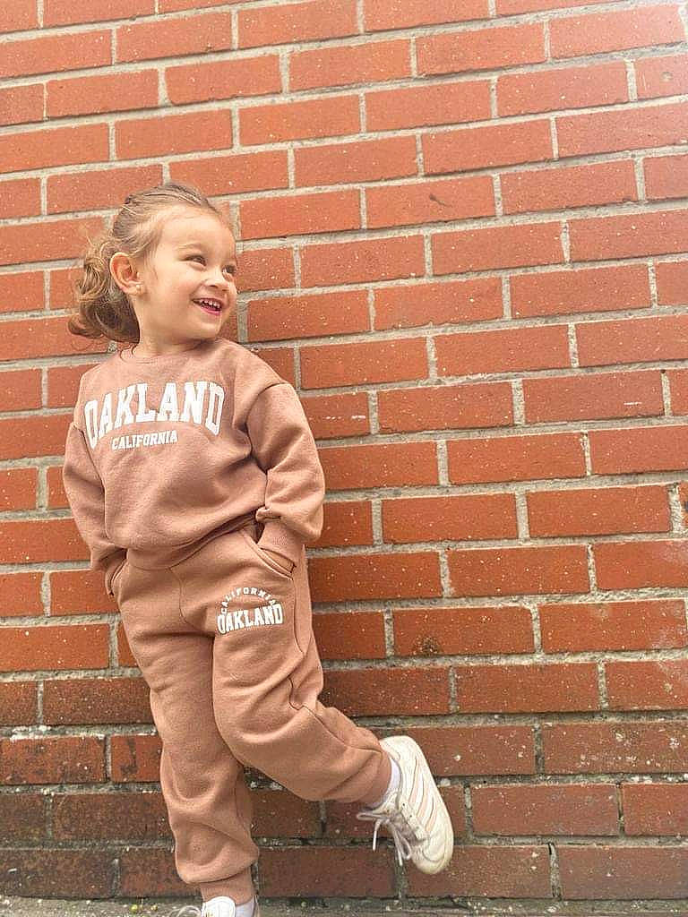Mina participe au concours pour gagner de l'argent avec cette photo : baby, brick, brickwork, child, eye, flooring, fun, gesture, grass, hair, happy, human_body, joy, orange, people_in_nature, person, sleeve, smile, standing, t_shirt