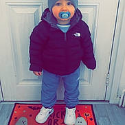 Luca joined the competition — help win amazing prizes! child, baby, pacifier, hat, jacket, sneakers, door, doormat, floor, indoor, clothing, standing, north_face, blue_pants, white_shoes, halloween, ghosts, trick_or_treat, cute, winter_wear