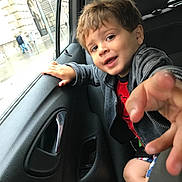 Trelly joined the competition — help win amazing prizes! child, boy, car_interior, backseat, window, smile, hand, seatbelt, jacket, shorts, playful, portrait, vehicle, urban, rainy, street, people, door_handle, window_glass, casual_clothing