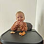 Aaron a rejoint le concours — aidez-le/la à gagner de superbes lots ! toddler, child, high_chair, bread, food, smile, happy, crumbs, table, wooden_table, tray, indoor, person, young_child, eating, clothing, face, light, wall, photograph