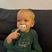 Aaron participe au concours pour gagner de l'argent avec cette photo : toddler, child, pacifier, green_clothing, sitting, couch, indoor, blond_hair, smiling, portrait, cute, cozy, baby, person, finger_pointing, long_sleeves, pants, expression, home, wall
