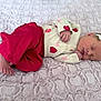 baby, newborn, sleeping, headband, bow, blanket, pink, red, heart_prints, pajamas, onesie, feet, hand, portrait, indoor, cozy, blanket_texture, infant, peaceful, soft