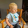 Gabriel participe au concours pour gagner de l'argent avec cette photo : toddler, child, boy, blue_eyes, bib, gray_tshirt, wooden_chair, indoor, thinking, sitting, casual_clothing, short_hair, cute, young_child, furniture, expression, portrait, home, daylight, real_photo