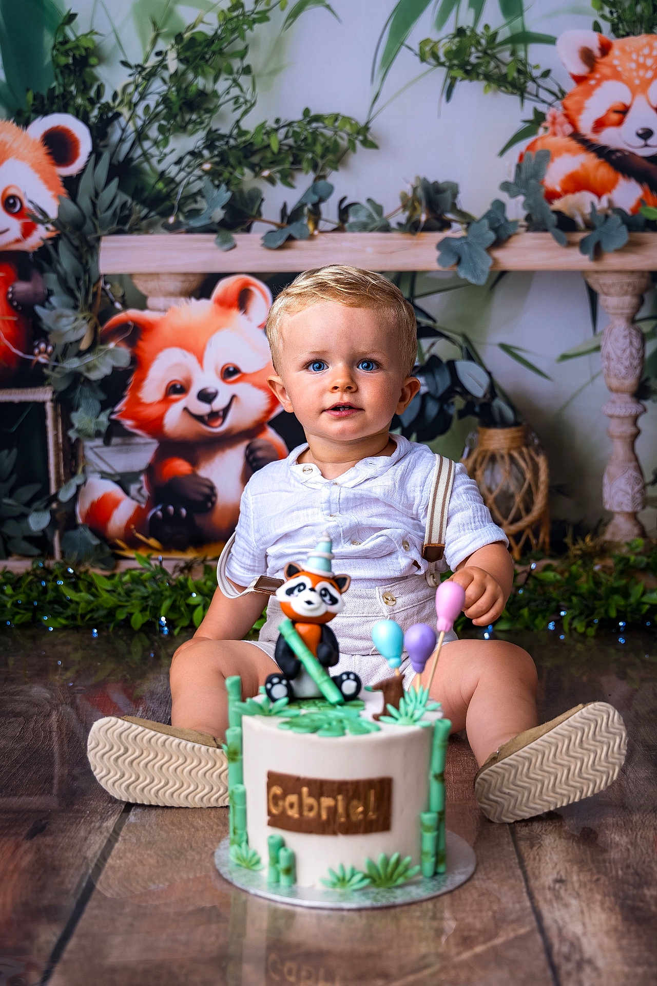 Gabriel a rejoint le concours — aidez-le/la à gagner de superbes lots ! toddler, child, cake, birthday, red_panda, toy, balloons, party, greenery, plants, floor, wooden_floor, white_clothing, suspenders, blue_eyes, cute, smiling, indoor, celebration, decorations