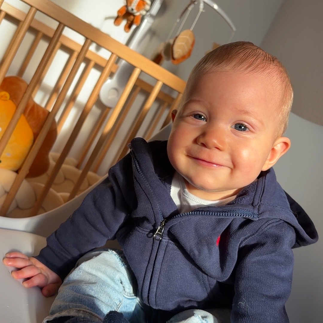 Milann participe au concours pour gagner de l'argent avec cette photo : baby, child, smiling, sitting, hoodie, jeans, socks, crib, mobile, toy, wooden_crib, indoor, sunlight, happy, portrait, face, person, infant, cute, casual_clothing