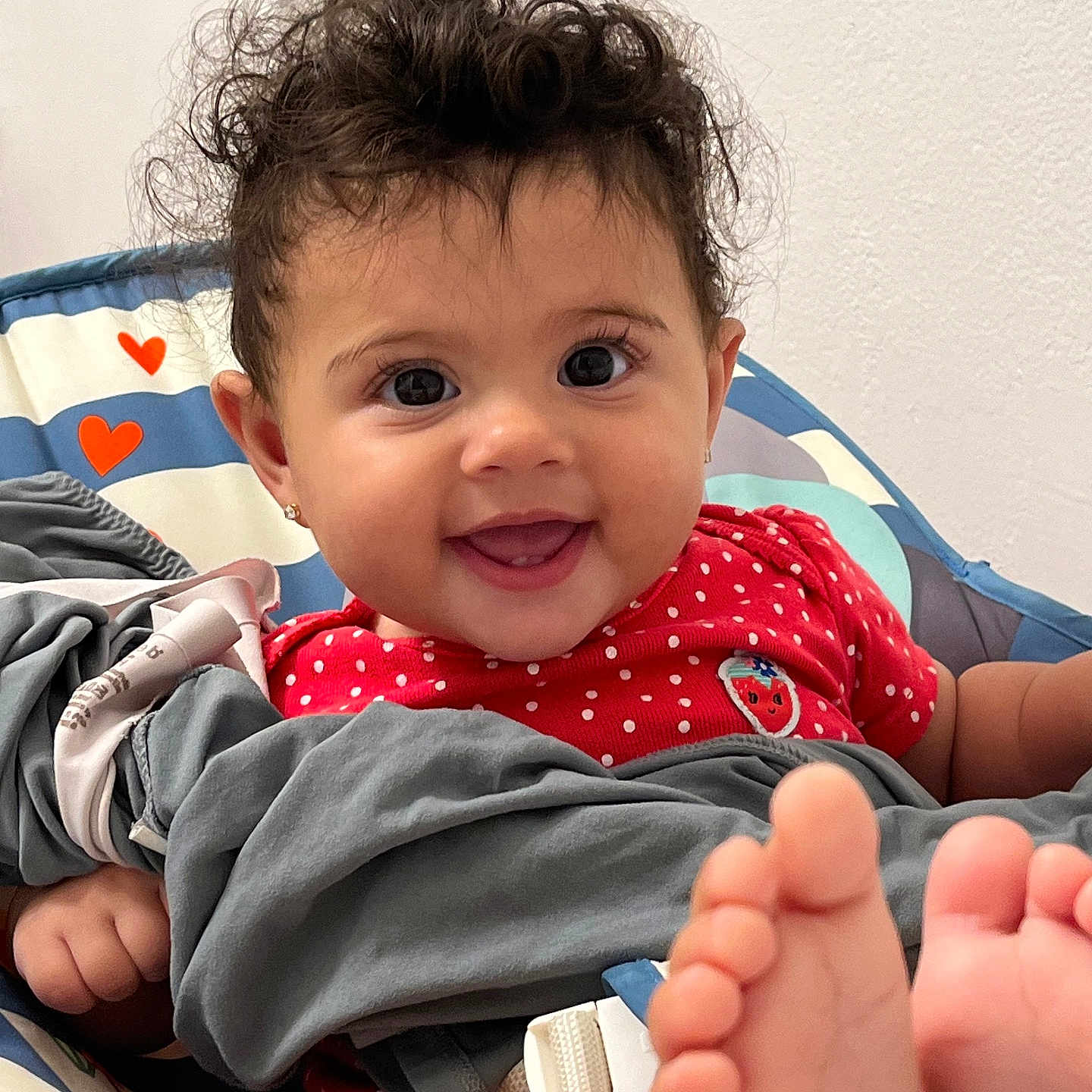 Maylani joined the competition — help win amazing prizes! baby, baby_seat, barefoot, blanket, child, curly_hair, cute, earrings, eyes, face, hands, happy, heart_pattern, indoor, infant, person, polka_dots, portrait, red_clothing, smiling