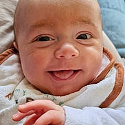 Noah participe au concours pour gagner de l'argent avec cette photo : baby, smiling, tongue_out, close_up, face, hand, bib, clothing, infant, cute, skin, expression, child, portrait, young, happy, indoors, cozy, background, person