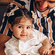 Aadya is registered to the contest to win money with this photo: toddler, child, adult, man, smile, hair_bow, striped_shirt, holding, affection, portrait, indoor, family, cute, love, happy, face, person, clothing, skin, closeup