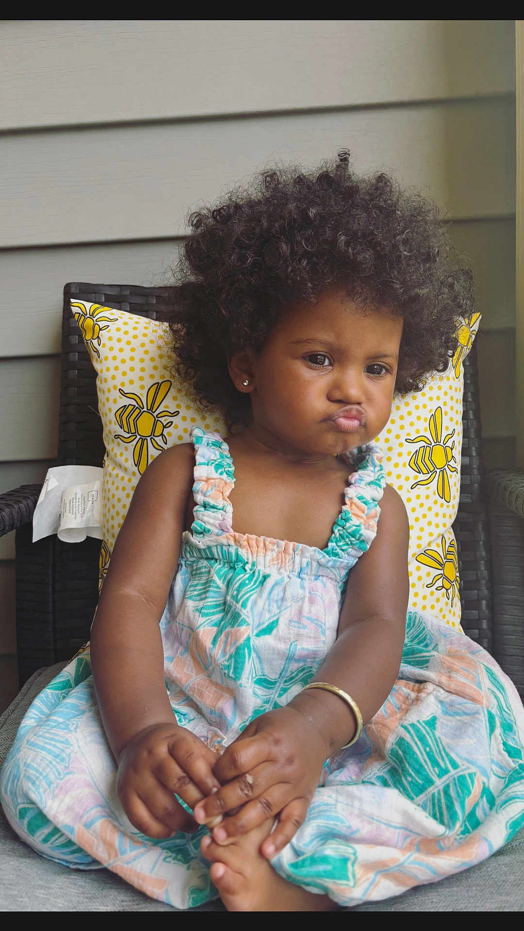 Ryver joined the competition — help win amazing prizes! toddler, child, afro_hair, curly_hair, pouty_face, dress, patterned_dress, chair, pillow, yellow_pillow, indoor, cute, baby, hands, feet, skin, earrings, bracelet, expression, portrait