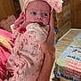 Autumn-Storm is registered to the contest to win money with this photo: baby, infant, pink, headband, flower, onesie, person, arm, hand, indoor, wooden_wall, bedspread, quilt, pattern, cute, newborn, holding, clothing, face, portrait