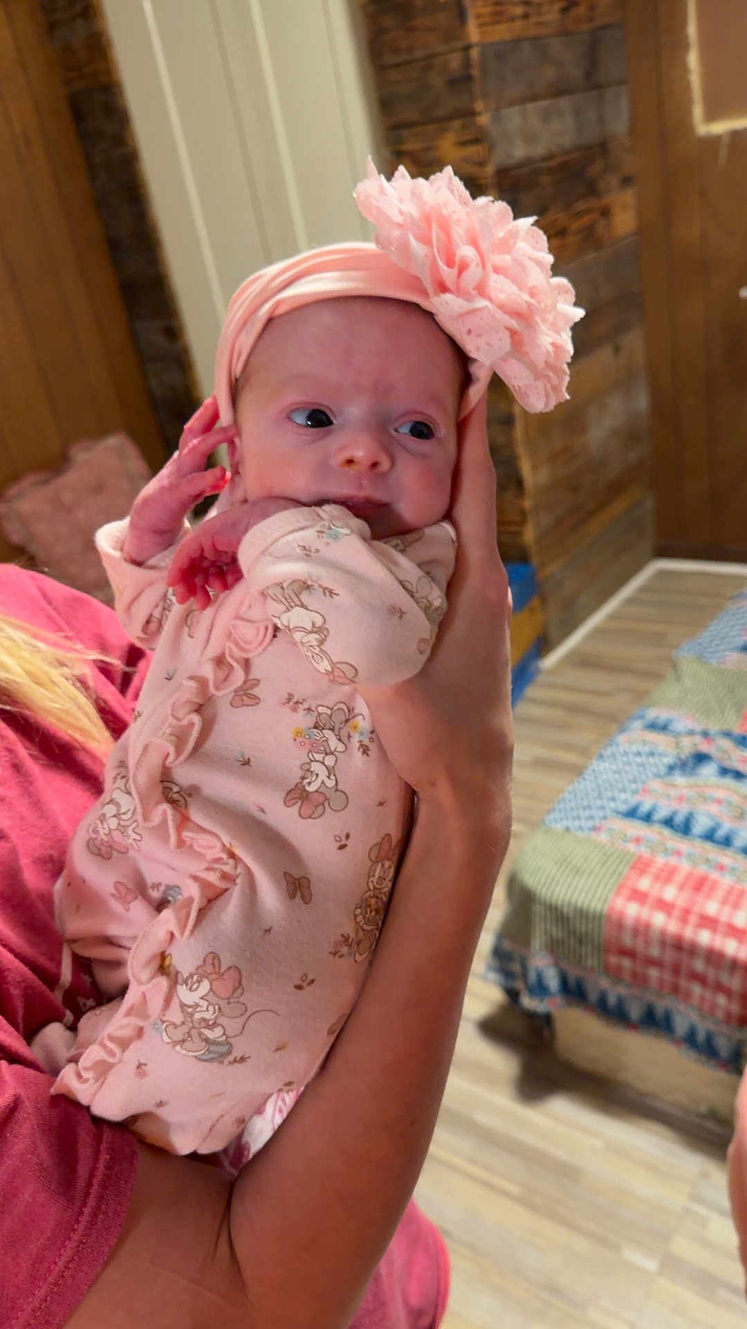 Autumn-Storm is registered to the contest to win money with this photo: baby, infant, pink, headband, flower, onesie, person, arm, hand, indoor, wooden_wall, bedspread, quilt, pattern, cute, newborn, holding, clothing, face, portrait