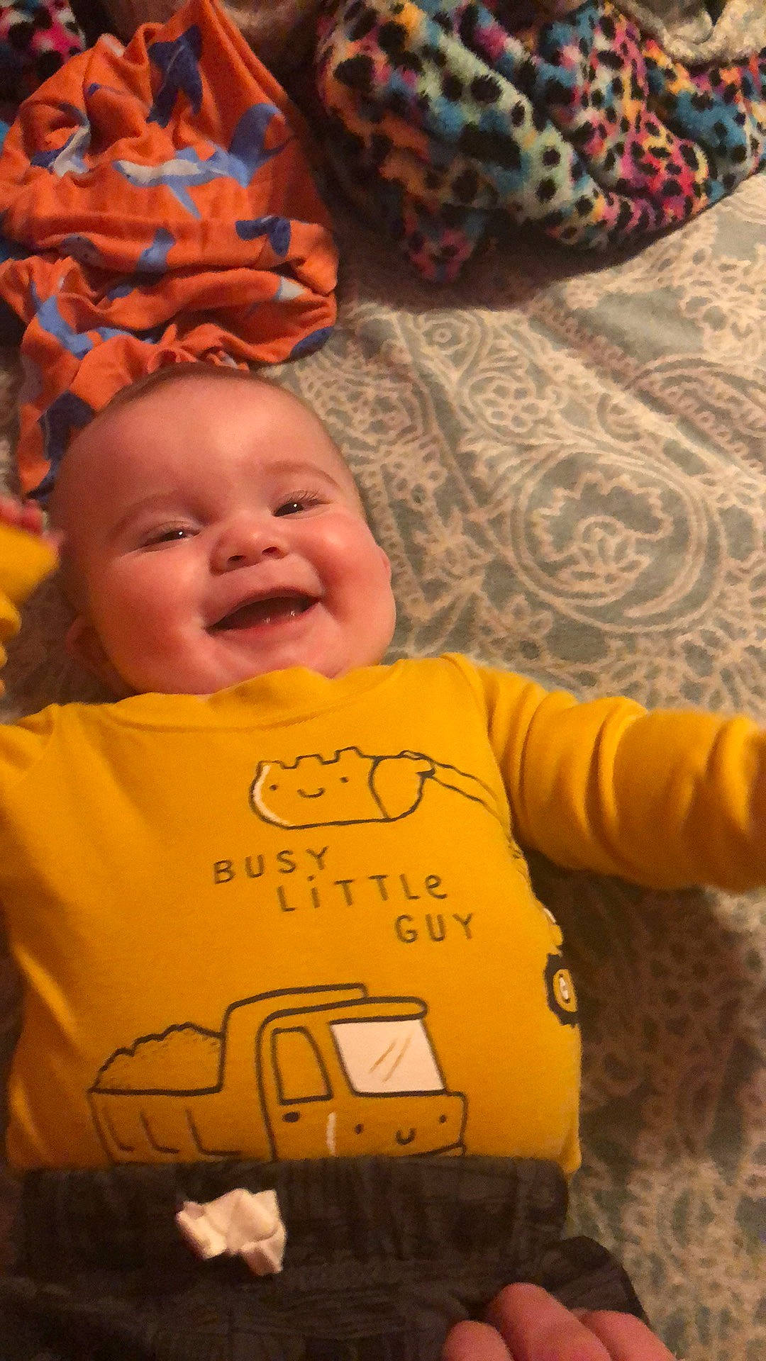 Shawn is registered to the contest to win money with this photo: baby, baby_laughing, baby_toddler_clothing, cheek, child, comfort, fun, grass, happy, head, human, laugh, orange, person, room, smile, t_shirt, toddler, tree, wood