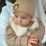 Eden participe au concours pour gagner de l'argent avec cette photo : baby, child, beanie, knitwear, mickey_mouse, hat, hands, face, blue_eyes, hoodie, white_clothing, person, closeup, portrait, warm_clothing, cute, indoor, holding, sweater, button