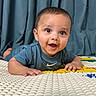 Nived is registered to the contest to win money with this photo: baby, child, toddler, smiling, indoor, play_mat, curtains, blue, happy, person, face, clothing, short_hair, skin, hands, lying_down, expression, cute, young, portrait