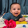 Nived is registered to the contest to win money with this photo: baby, child, smiling, happy, indoor, curtains, flower, colorful_mat, toddler, reaching, playtime, clothing, person, face, bright_colors, joy, cute, portrait, young_child, expression