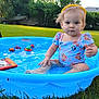 Phoebe is registered to the contest to win money with this photo: toddler, child, pool, water, blue, grass, outdoor, summer, toy, splash, yellow_headband, cute, baby, sitting, play, sunlight, greenery, fun, clothing, portrait