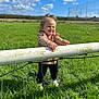 Julia a rejoint le concours — aidez-le/la à gagner de superbes lots ! toddler, child, smiling, outdoor, grass, fence, blue_sky, clouds, sunny, field, nature, happy, standing, person, casual_clothing, daytime, greenery, playful, cute, young_child