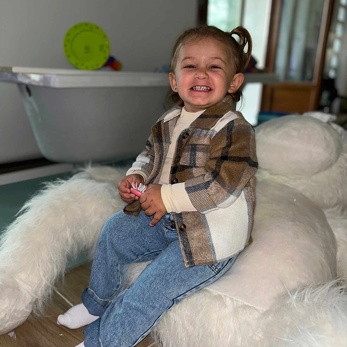 Julia participe au concours pour gagner de l'argent avec cette photo : bathtub, child, cozy, cushion, cute, floor, furniture, happy, home, indoor, jeans, person, plaid_jacket, portrait, seated, smiling, socks, stuffed_animal, toddler, wooden_floor