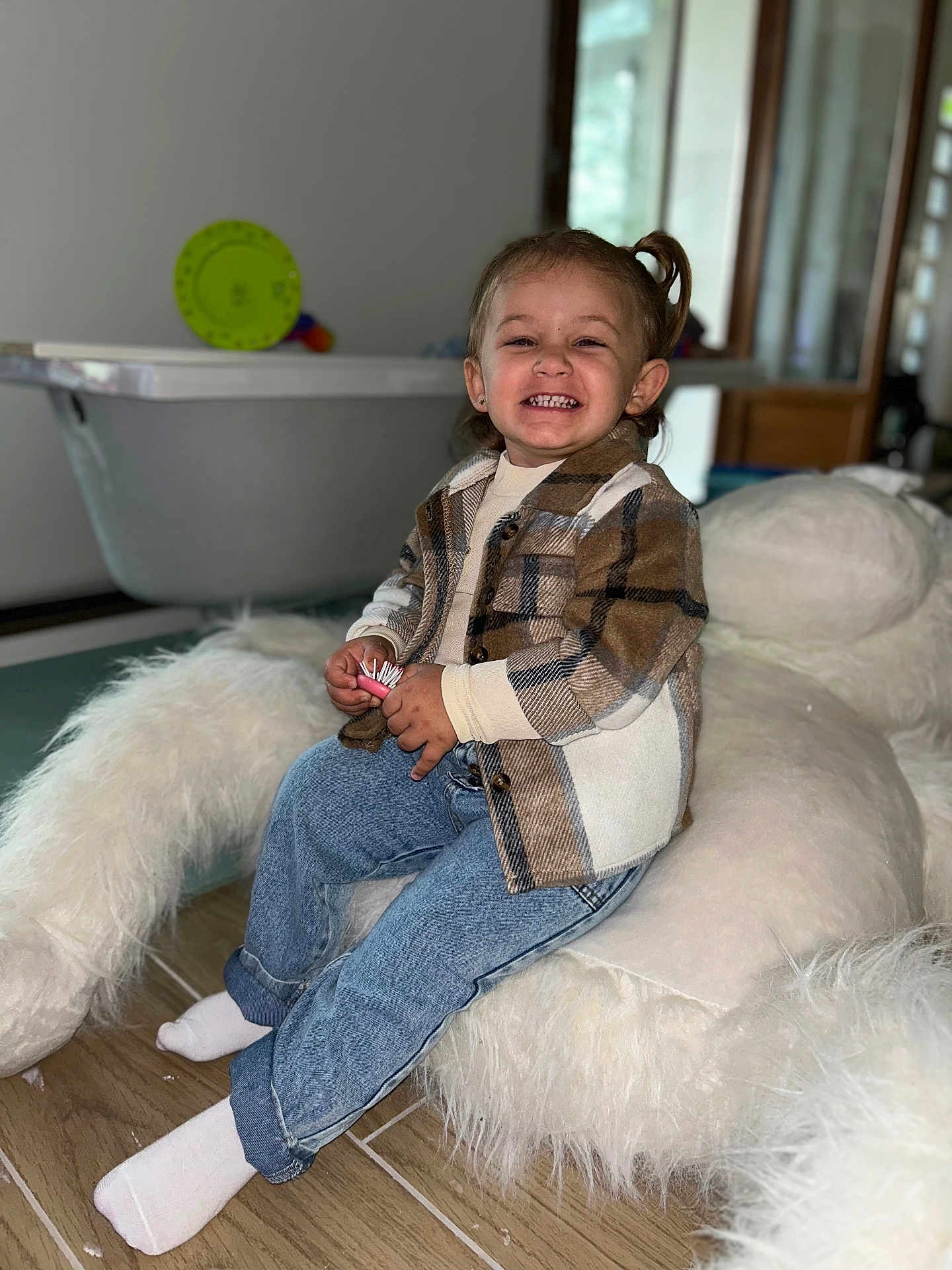 Julia participe au concours pour gagner de l'argent avec cette photo : bathtub, child, cozy, cushion, cute, floor, furniture, happy, home, indoor, jeans, person, plaid_jacket, portrait, seated, smiling, socks, stuffed_animal, toddler, wooden_floor