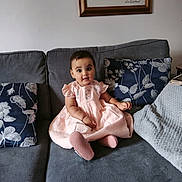Aaliyah joined the competition — help win amazing prizes! baby, child, pink_dress, couch, sofa, cushion, blanket, indoor, portrait, smiling, face, person, seated, home, decor, furniture, photography, young_child, happy, cute