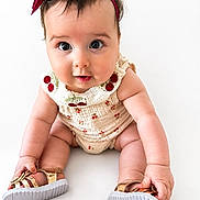 Livia is registered to the contest to win money with this photo: baby, child, infant, cute, headband, bow, cherry_pattern, sitting, golden_sandals, white_background, curious_eyes, chubby_cheeks, clothing, footwear, portrait, young, person, studio_photo, innocent, adorable