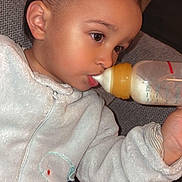 Raphaël participe au concours pour gagner de l'argent avec cette photo : child, baby, toddler, feeding_bottle, milk, onesie, cozy, sofa, couch, portrait, closeup, face, eyes, ear, hand, indoors, pajamas, bottle_nipple, soft_fabric, relaxed