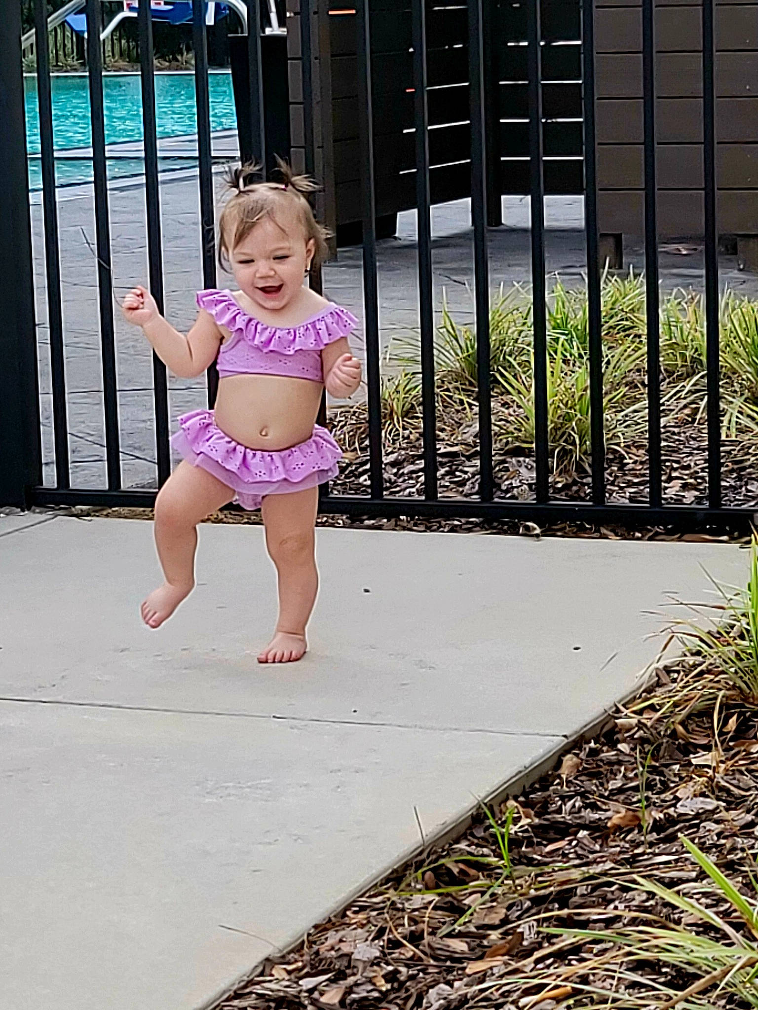 Caroline is registered to the contest to win money with this photo: baby, baby_toddler_clothing, barefoot, child, fence, foot, grass, happy, home_fencing, human_leg, joy, leg, leisure, person, plant, recreation, shorts, sitting, thigh, toddler