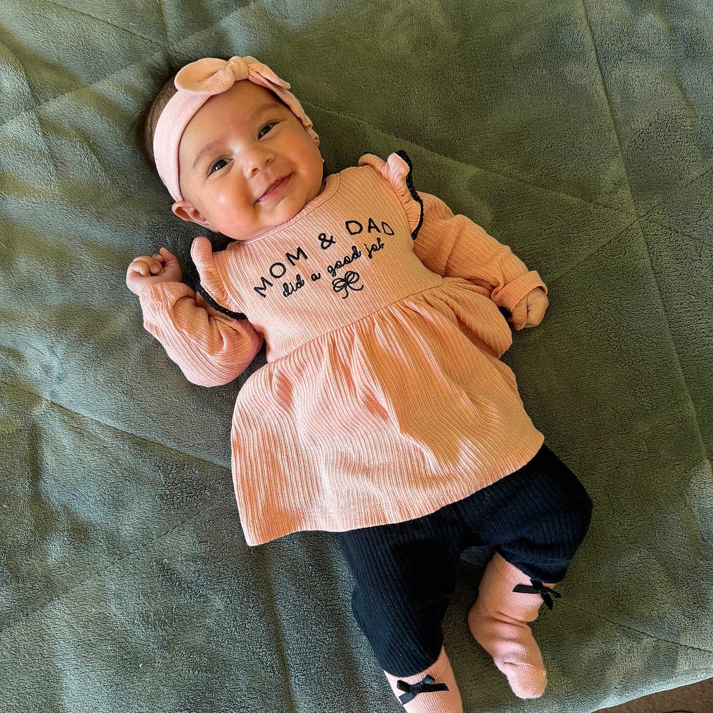 Kalia joined the competition — help win amazing prizes! baby, infant, smile, pink_clothing, headband, socks, blanket, soft_texture, lying_down, happy, cute, child, face, indoors, portrait, apparel, person, young, cozy, resting