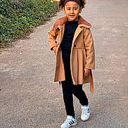 Nour participe au concours pour gagner de l'argent avec cette photo : child, young, walking, path, outdoor, coat, tan_coat, black_clothing, sneakers, headband, curly_hair, greenery, park, sunlight, casual, fashion, confident, person, nature, sidewalk