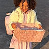 Nour participe au concours pour gagner de l'argent avec cette photo : child, girl, curly_hair, pigtails, smiling, basket, pink_basket, pink_backpack, white_jacket, fluffy_jacket, dress, tights, outdoor, pavement, sunlight, shadow, happy, holding, person, cute