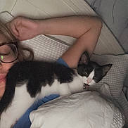 Dottie is registered to the contest to win money with this photo: bed, black_and_white_cat, blanket, cat, closeup, comfort, cozy, cuddling, feline, glasses, headboard, home, indoor, nap, person, pillow, relaxing, resting, sleeping, soft