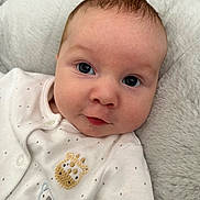 Harry is registered to the contest to win money with this photo: baby, infant, close_up, face, eyes, onesie, animal_embroidery, cute, soft_texture, plush, white_clothing, portrait, child, newborn, skin, head, expression, indoors, comfort, cozy