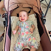 Leane joined the competition — help win amazing prizes! baby, smiling, stroller, floral_outfit, socks, child, indoor, carpet, pillow, seated, blue_chair, happy, person, infant, home, fabric, toy_stroller, light, candid, relaxed
