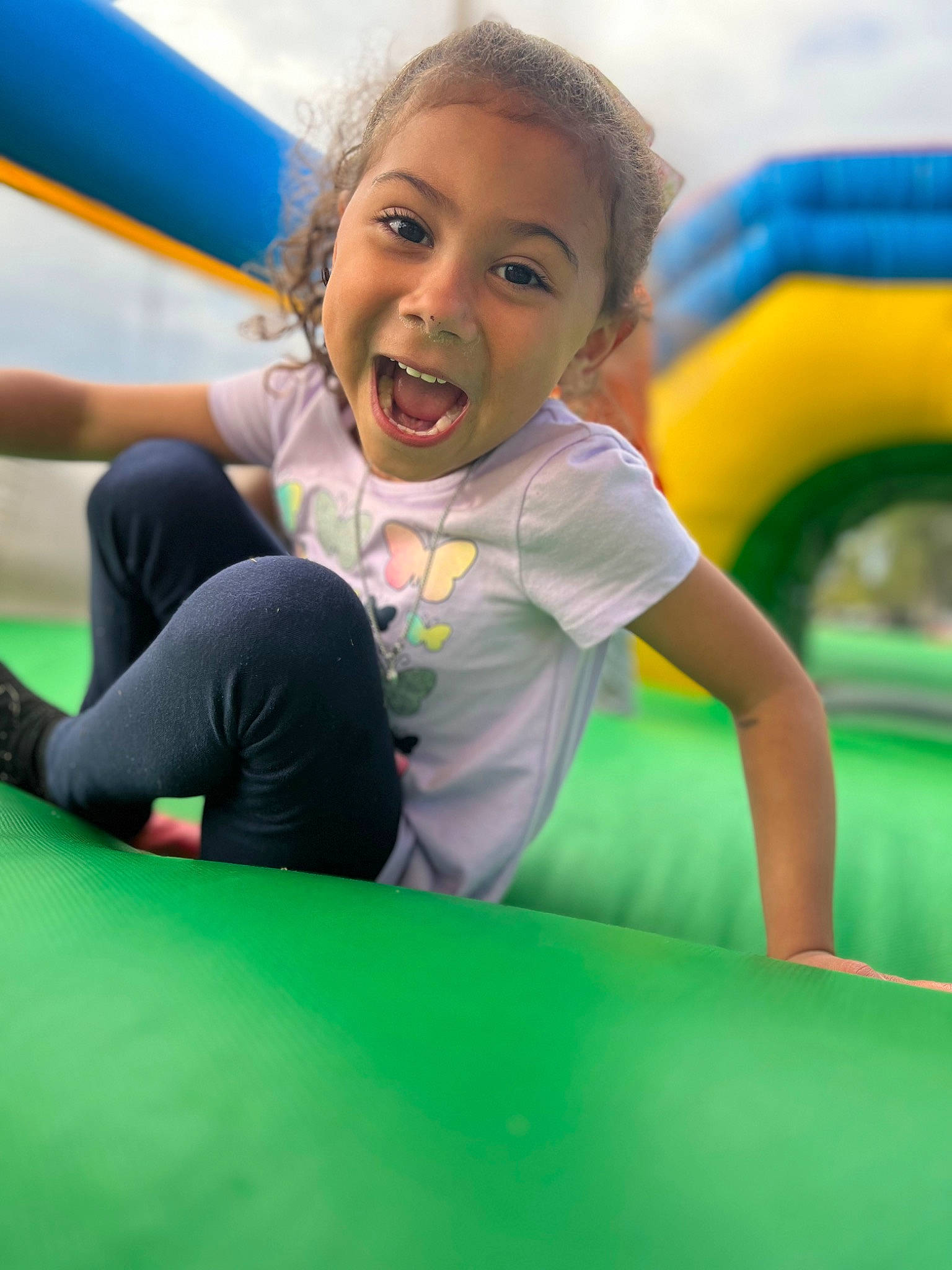 Avah Jean is registered to the contest to win money with this photo: bounce_house, child, chute, fun, grass, happy, inflatable, laugh, leisure, nonbuilding_structure, outdoor_play_equipment, outdoor_recreation, person, play, playground, recreation, sky, smile, t_shirt, toddler