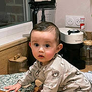 Emilio participe au concours pour gagner de l'argent avec cette photo : child, toddler, baby, pajamas, bear_prints, kitchen, countertop, coffee_machine, nespresso, blender, hardwood_floor, window, jar, bottle, outlet, curious, crawling, hand, face, big_eyes