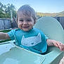 Ethan a rejoint le concours — aidez-le/la à gagner de superbes lots ! toddler, child, high_chair, bib, smiling, messy_face, food, outdoor, daylight, sky, grass, wooden_deck, fence, trees, happy, person, cute, playful, blue, portrait