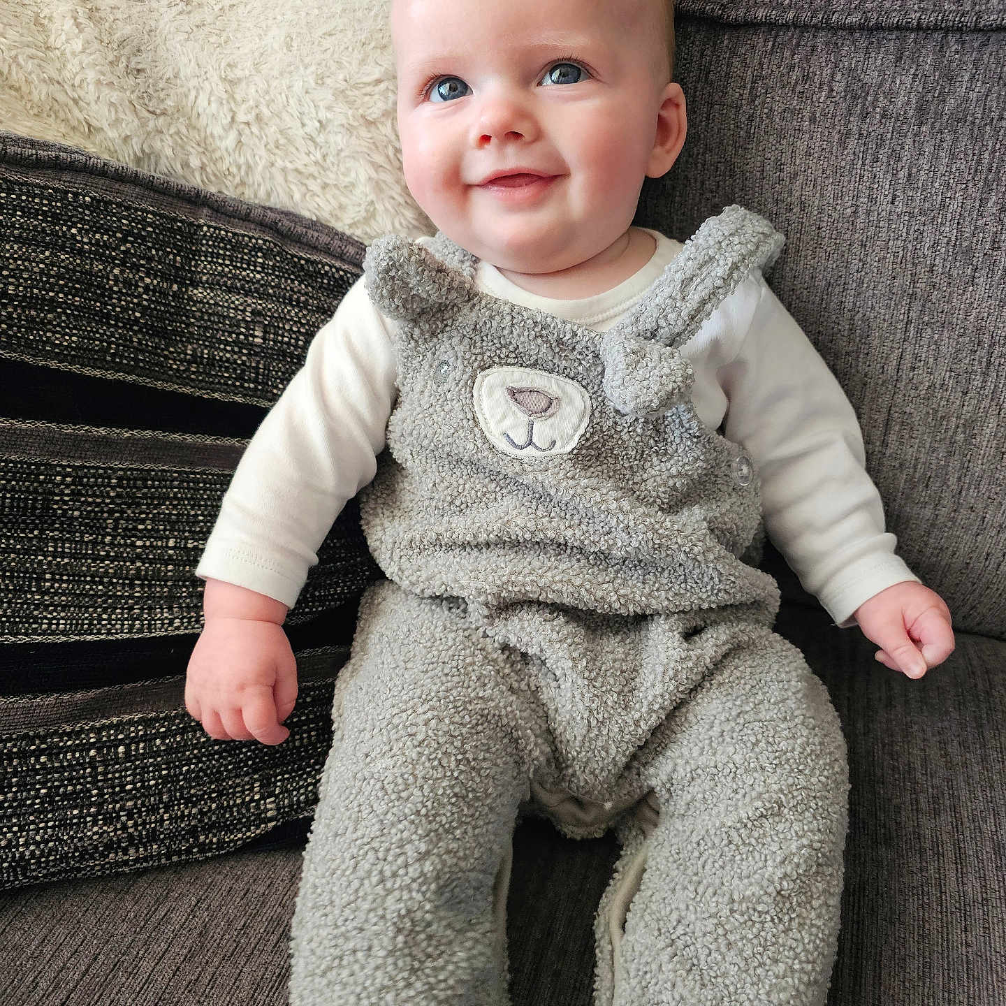 Elijah joined the competition — help win amazing prizes! baby, babylaughing, blanket, clothing, couch, cushion, face, furniture, happy, head, homedecor, jeans, knitwear, pants, person, photography, portrait, sitting, smile, sweater
