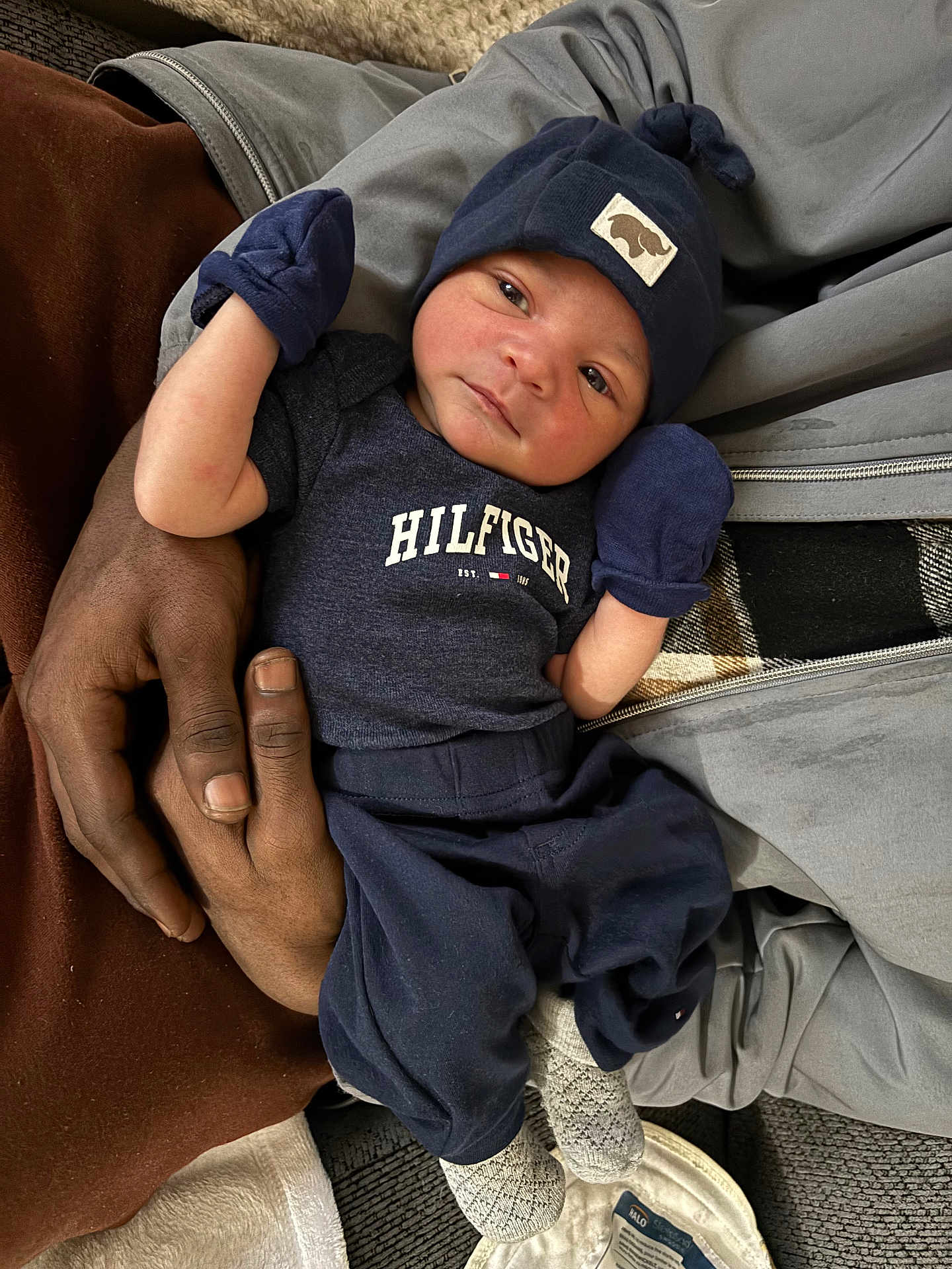 Jameon joined the competition — help win amazing prizes! child, baby, infant, newborn, hat, mittens, onesie, clothing, person, hands, adult_hand, couch, blanket, socks, knit_cap, portrait, reclining, closeup, indoor, cozy