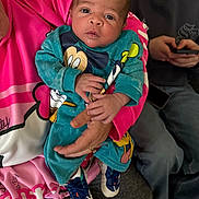 Jameon is registered to the contest to win money with this photo: adult, baby, blue_shoes, casual_clothing, child, clothing, cozy, curious, face, family, hand, holding, indoor, infant, mickey_mouse, person, phone, pink_garment, portrait, sitting