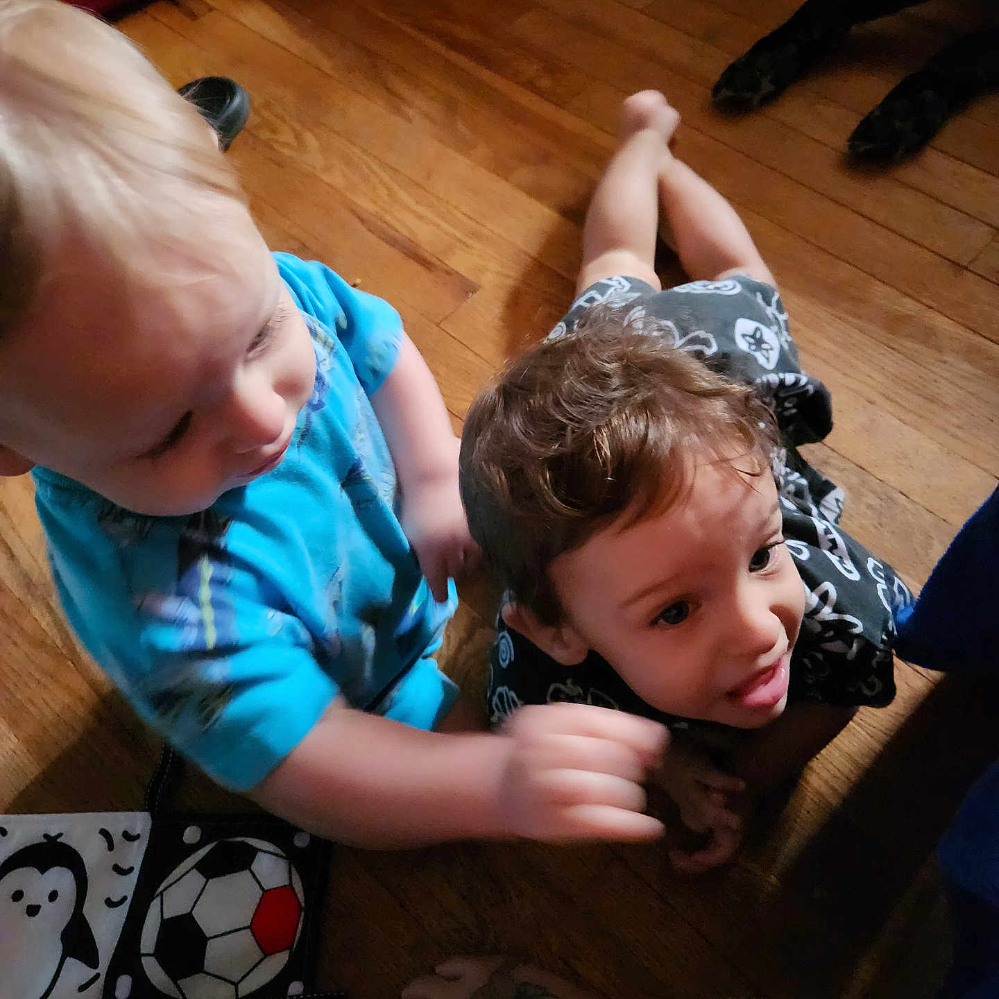 Zane And Rayden joined the competition — help win amazing prizes! baby, blue_shirt, candid, casual_clothing, child, curly_hair, expression, floor, foot, hand, indoor, interaction, penguin, person, playful, soccer_ball, tattoo, toddler, toy, wooden_floor