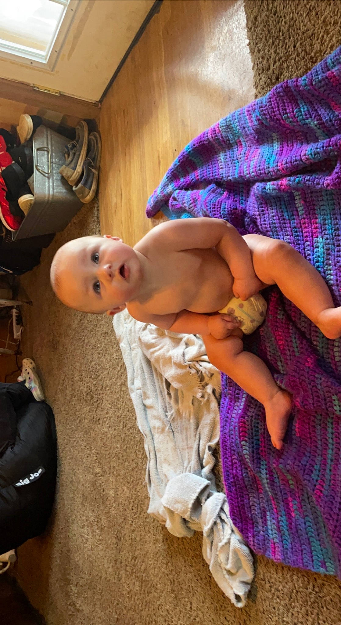 Kai is registered to the contest to win money with this photo: abdomen, baby, barechested, chest, child, comfort, elbow, flooring, fun, human_leg, joint, magenta, pattern, person, purple, room, sitting, skin, surprise, thigh
