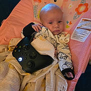 Summer is registered to the contest to win money with this photo: baby, infant, xbox_controller, blanket, pacifier, pink_chair, animal_print, cute, indoor, child, seat, relaxed, cozy, toy, gaming, young, person, comfort, portrait, casual