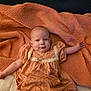 arm, baby, blanket, child, clothing, comfort, cute, dress, fabric, face, happy, head, indoor, infant, laying_down, orange, portrait, skin, smiling, soft_texture