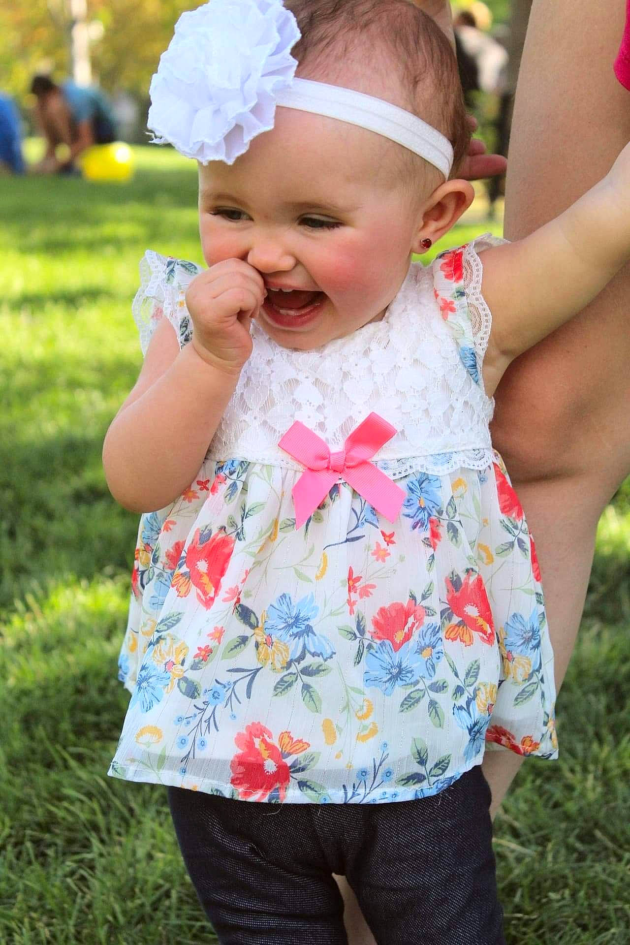 Londynn is registered to the contest to win money with this photo: baby, baby_toddler_clothing, blue, child, dress, fun, gesture, grass, green, happy, headwear, magenta, pattern, people_in_nature, person, photograph, pink, plant, sleeve, smile