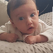 Isabella joined the competition — help win amazing prizes! baby, infant, child, face, eyes, expression, blanket, texture, white_clothing, lying_down, indoors, couch, soft_light, curious, portrait, skin, hand, young, cute, head