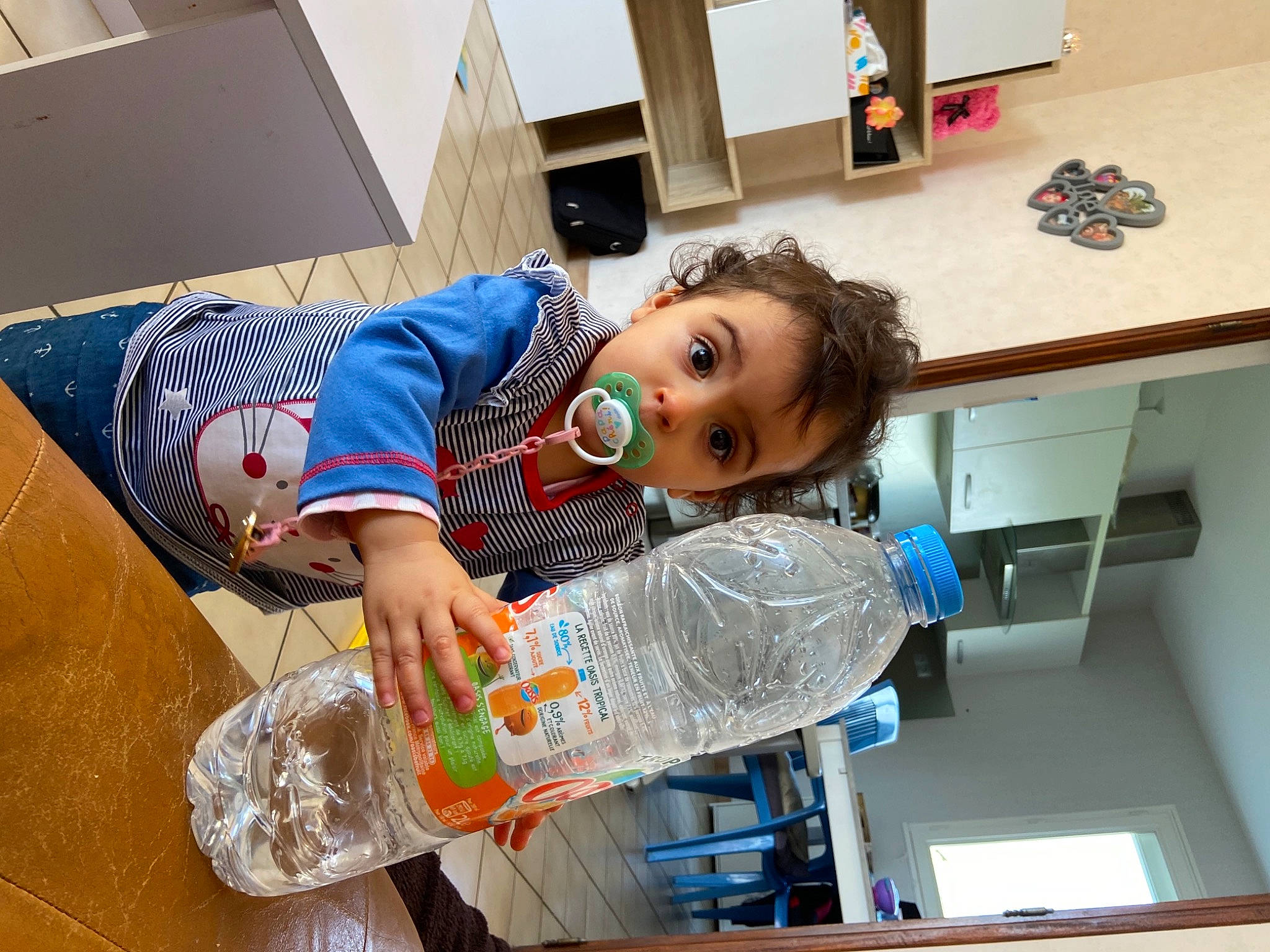 Cassie participe au concours pour gagner de l'argent avec cette photo : baby, bottle, cabinetry, child, cooking, cupboard, drawer, drinking_water, drinkware, flooring, kitchen, paint, person, plastic, plastic_bottle, play, refrigerator, room, service, surprise
